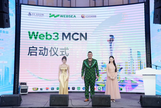 Three presenters stand on stage at a Web3 MCN launch ceremony, with the large screen behind them displaying "Web3 MCN 启动仪式" alongside logos for SV SHOW, Websea, and another partner. The central man wears a green patterned suit, flanked by two women in gold and pink dresses, marking the formal announcement of Websea's Proof of Reserve initiative during the Kazakhstan speaking event.