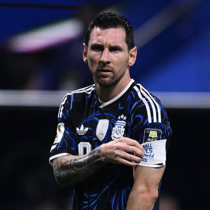 A photo of Lionel Messi wearing the Argentina national team's away kit with a dark patterned design, wearing a captain's armband.
