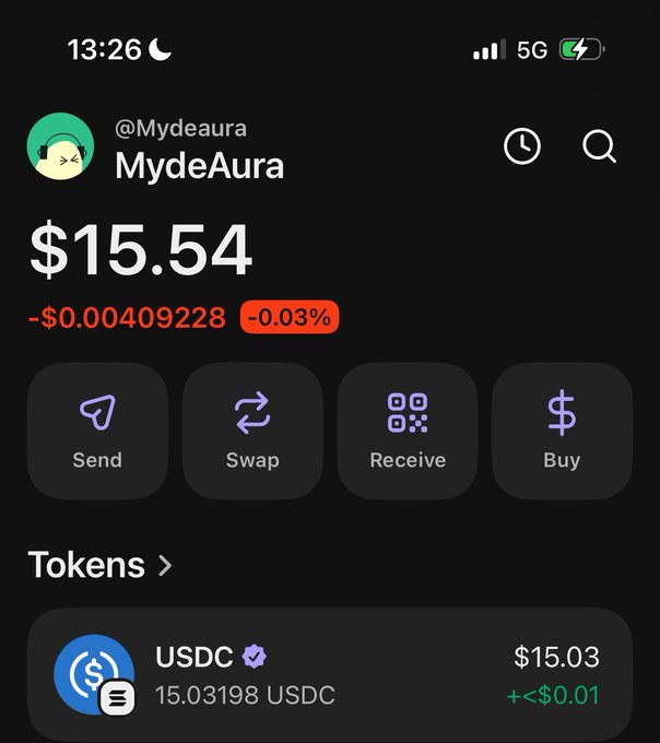 A screenshot of a Phantom crypto wallet showing the account "MydeAura" with a balance of $15.54 (down -$0.00409228 at -0.03%), containing 15.03198 USDC worth $15.03. The modest balance visually reinforces the post's context, where the user considers gifting around $5 each to three mutual followers despite having limited funds available.