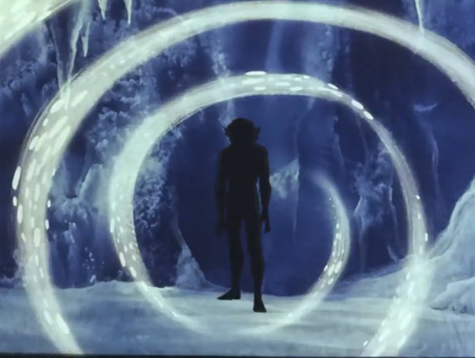 A silhouette of a figure stands in an icy cave surrounded by swirling, glowing blue energy rings in an animated scene.