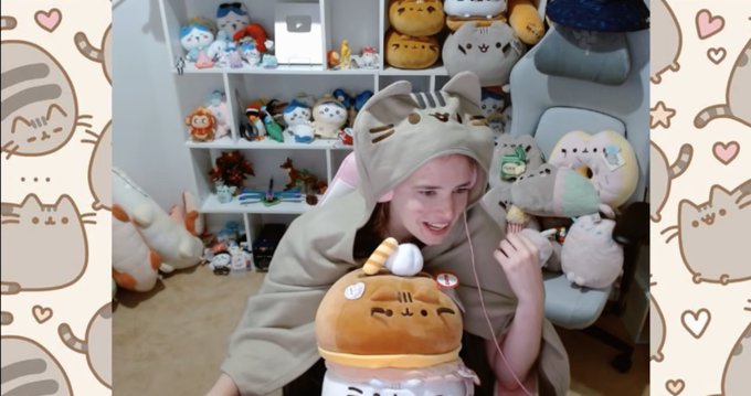 A young woman wearing a cat-themed hoodie sits in front of a shelf full of plush toys, including a Pusheen-style cat plush, while framed by decorative Pusheen borders.