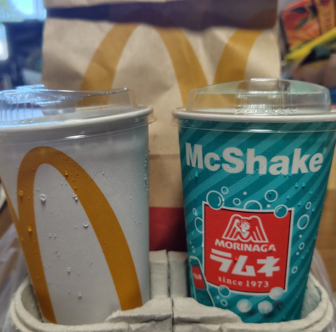 A McDonald's Happy Meal set featuring two drinks—a generic cup with the iconic golden arches and a teal McShake cup branded with "Morinaga Ramune since 1973"—sits in a drink carrier, directly tying to the poster's enthusiasm for the rare Morinaga Ramune collaboration at McDonald's.