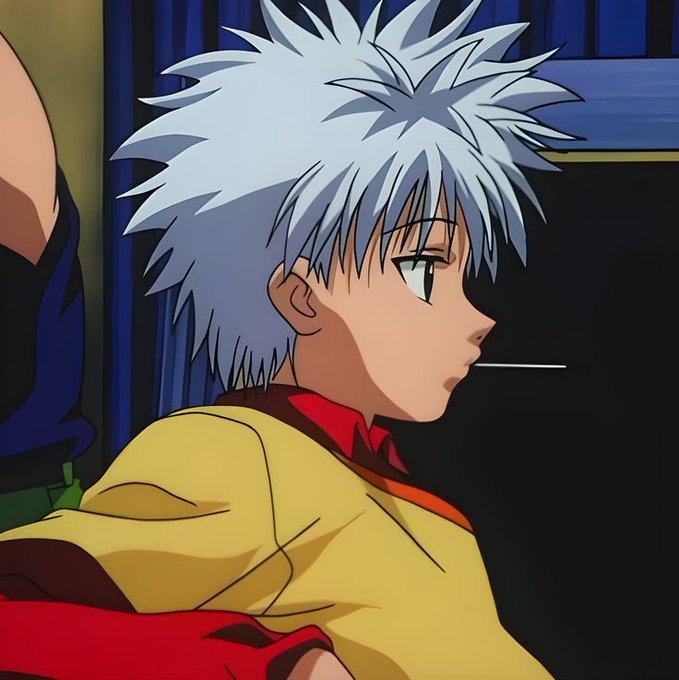 A side-profile anime screenshot of a silver-haired character in a yellow and red outfit with a thin object in his mouth.
