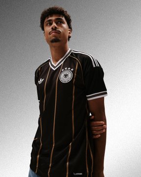 A young man models a black German national football team jersey featuring the DFB crest and three stars on the collar.