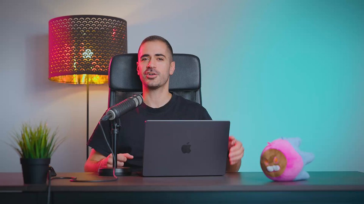 The image features a man sitting at a desk with an open laptop computer. The background of the image shows a green wall behind him. There are two pink stuffed animals placed next to each other, one on top of the other. A potted plant is also visible in the scene. The post that accompanies this image discusses the current state of the crypto market and mentions Bitcoin Core as an example of a narrative that has been dominating the conversation recently.