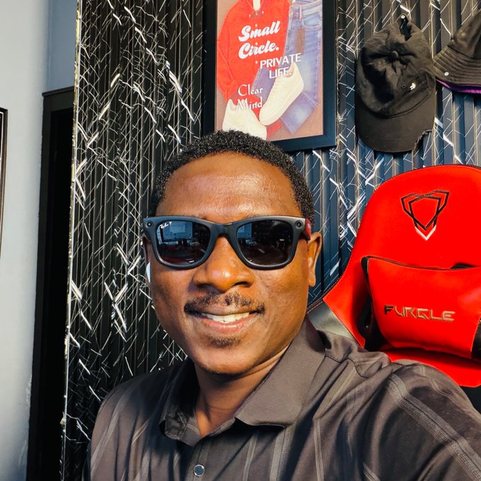 A smiling man wearing dark sunglasses and a black shirt poses for a selfie in front of a red gaming chair labeled "FURGLE" and a framed poster reading "Small Circle, Private Life, Clear Mind," with baseball caps hanging on a metallic wall behind him — visually echoing his message about sharing knowledge and expanding one's circle in web3.