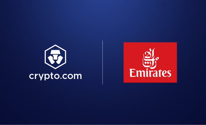 The image shows the Crypto.com logo on the left alongside the Emirates airline logo on the right against a dark blue background, illustrating their new partnership that enables Emirates customers to use Crypto.com Pay as a digital payment method for booking flights on emirates.com and the Emirates app.