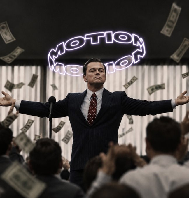 A man in a pinstripe suit and red tie stands at a microphone with his arms outstretched as dollar bills fall around him, beneath a glowing, rotating neon sign that reads "MOTION."