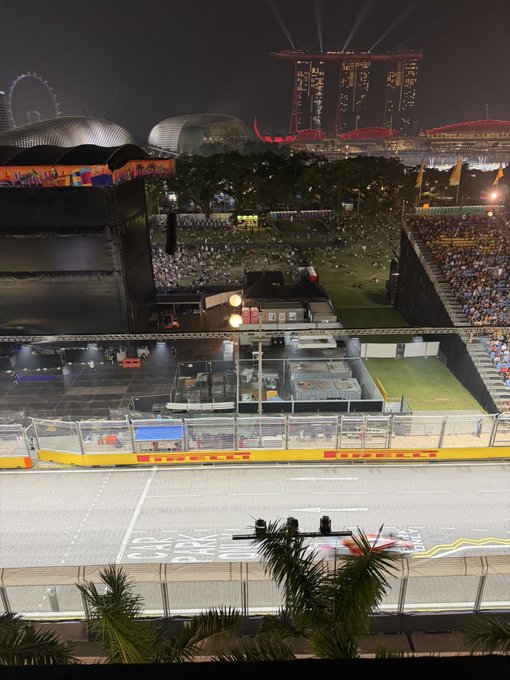 A nighttime view of a Formula 1 street circuit in Singapore, with the Marina Bay Sands hotel and Singapore Flyer visible in the background.