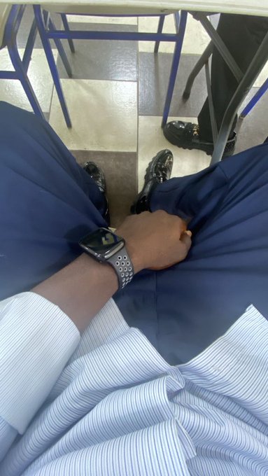 A first-person perspective photo showing legs in dark pants and black loafers, with one hand wearing an Apple Watch resting on the lap.
