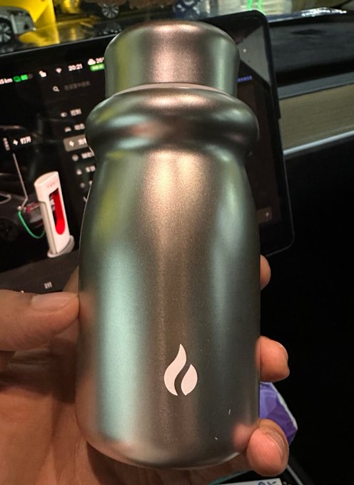 A hand holds a sleek metallic thermos featuring a flame-like logo, presented as an exquisite 13th-anniversary gift from HTX. The caption highlights appreciation for the thoughtful item, noting it as a perfect gift for his wife while wishing the company continued success under its leaders.