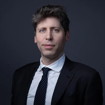 A formal portrait of a man in a dark suit, white shirt, and patterned tie against a gray background.