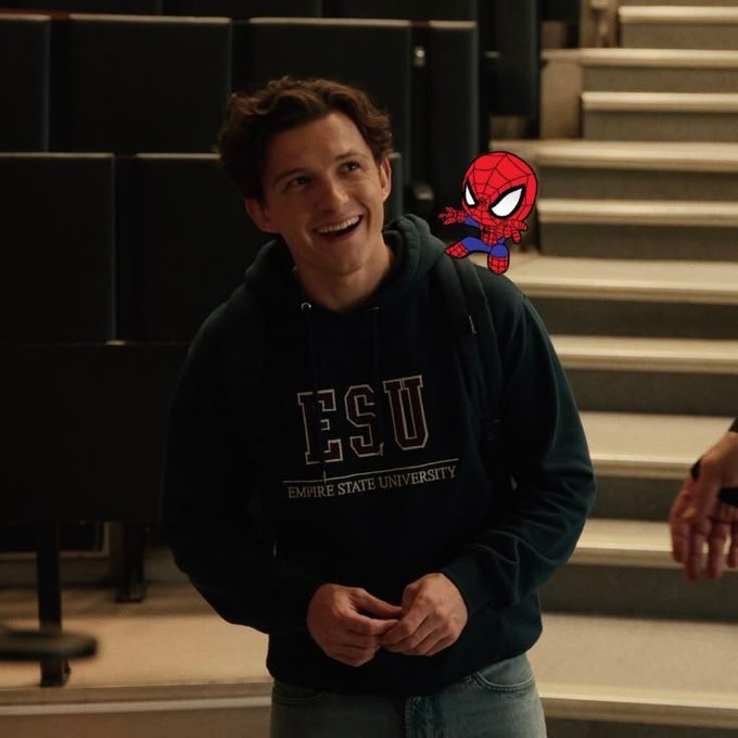 A young man in an ESU (Empire State University) hoodie smiles in an auditorium setting, with a Spider-Man graphic digitally added next to his shoulder.