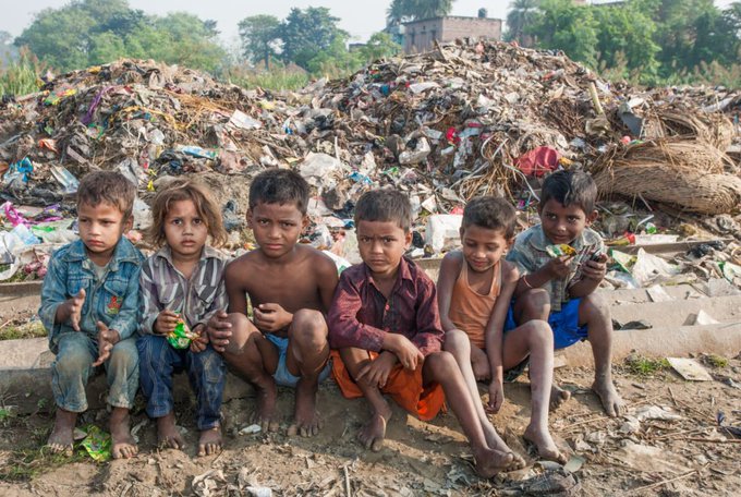 Six children sit barefoot and somber in front of a massive pile of garbage, a heartbreaking scene that underscores Dr. Nguyen's plea urging future XRP millionaires to remember to feed the hungry children in their communities.