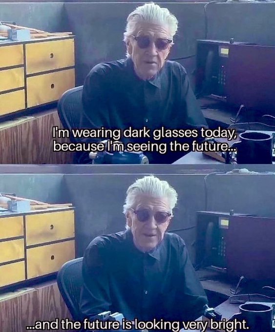 An older man with white hair and dark sunglasses sits in an office, with subtitles reading "I'm wearing dark glasses today, because I'm seeing the future..." and "...and the future is looking very bright." The image's playful caption about a bright future humorously contrasts with the post's ironic tone about the Fed "not printing money" while actually printing more, poking fun at those who remain bearish on crypto and gold despite this monetary backdrop.