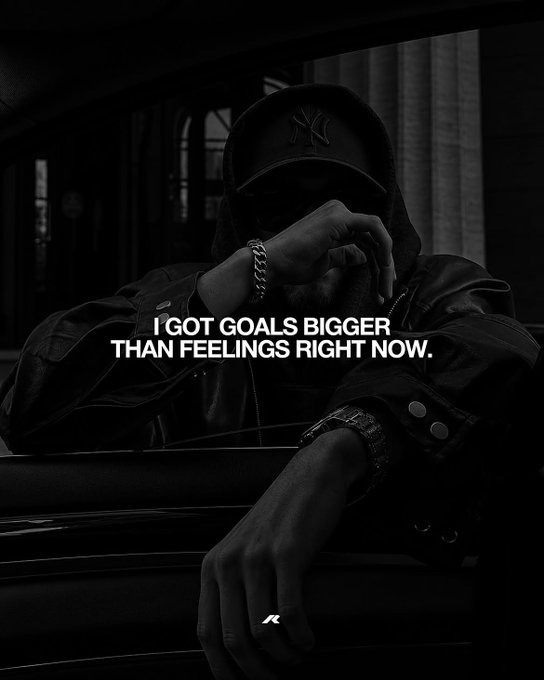 A moody, black-and-white photograph shows a person wearing a New York Yankees cap and dark jacket, leaning on a car, with the text overlay 'I GOT GOALS BIGGER THAN FEELINGS RIGHT NOW.'