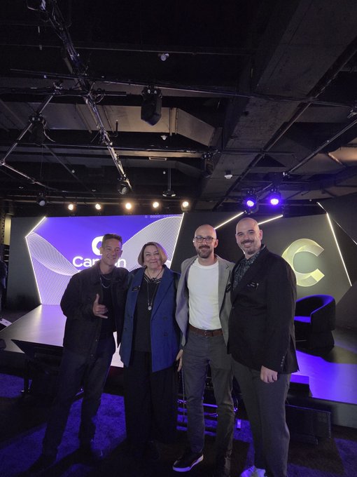 Group photo of four people posing together at what appears to be a Carbon-related event, with a 'Carbon' logo visible on the stage screen behind them.