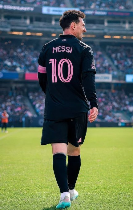 A soccer player wearing a black jersey with "MESSI" and the number "10" in pink stands on a green field, viewed from behind as he looks off to the side. The image appears unrelated to the accompanying post about NomismaNetwork's AI and infrastructure concept, with no visible connection between the athlete and the technology platform mentioned.