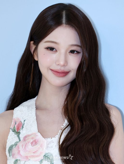 A portrait of a smiling woman with long brown hair wearing a white sleeveless top adorned with pink rose embroidery; 'STARNEWS' is visible at the bottom.