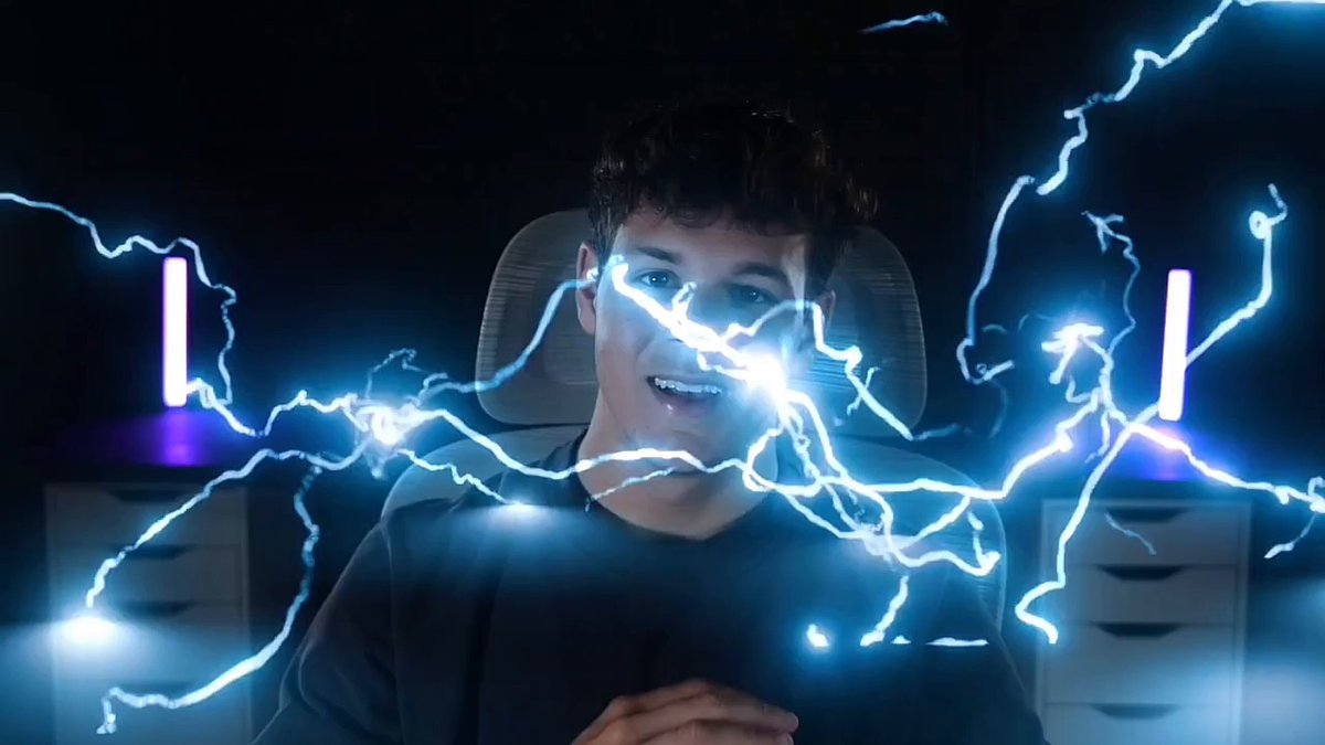 The image features a man sitting in front of two blue lights, with his face illuminated by a bright light that looks like lightning bolts. The background appears dark, which contrasts with the vibrant colors of the lights. There are also some text elements present in the image, including "Why $TROLL is Going to Lead the Next Cycle..." and "Focus on what is in the image".