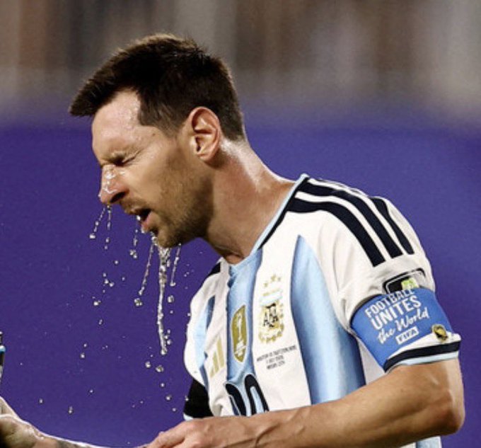Lionel Messi, wearing the Argentina national team jersey with a 'Football Unites the World 2023' captain's armband, is captured mid-spit during a match.