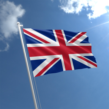 The Union Jack flag of the United Kingdom waving against a blue sky with white clouds and sunlight in the upper right corner.