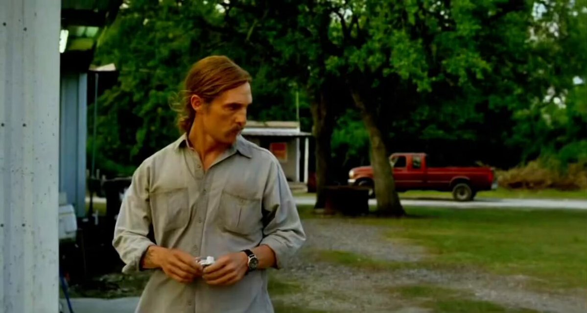 iced tea and a cigarette, with a red pickup truck parked nearby, against an overcast sky.