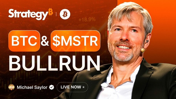 The image features a man sitting down with his arms crossed, wearing a black suit jacket. The background of the image has an orange hue that stands out against the white text displayed below him. Below the man's photo, there are two buttons labeled "BTC" and "BTC & $MSTR Bullrun". These buttons represent Bitcoin and Btc trading respectively. The post also includes a link to a video where Michael Smithson is talking about the strategy behind these trading buttons.