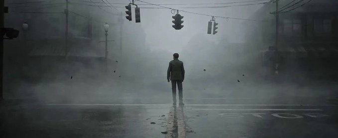 A lone figure in a dark jacket stands in the middle of a deserted street intersection under foggy, dim traffic lights, with another shadowy figure faintly visible in the distance.