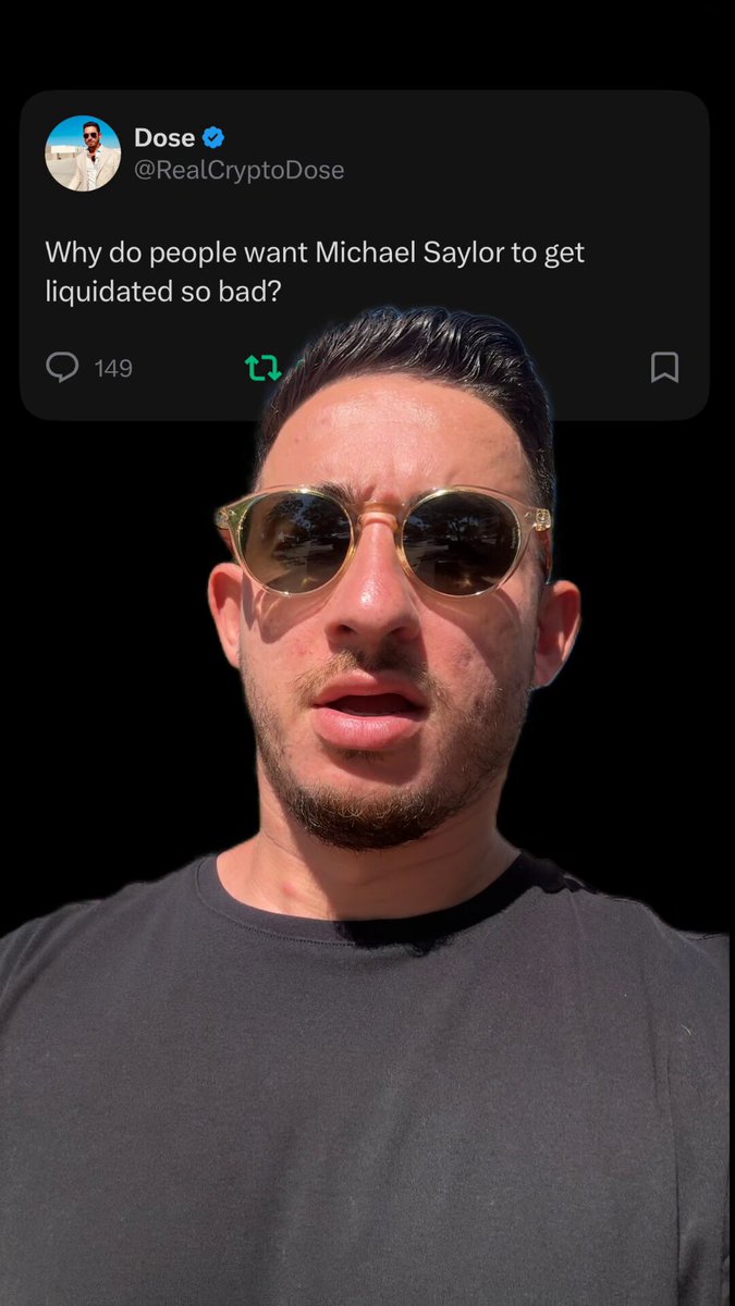 The image features a man wearing sunglasses, with his face partially obscured by them. He appears to be looking at the camera or someone else's face behind him. The caption of the image reads "Why do people want Michael Taylor to get liquidated so? Bitcoin is COOKED". This statement seems to be a humorous response to a post about Bitcoin and Michael Taylor, suggesting that the man might be making fun of the idea of liquidating Bitcoin or expressing his disagreement with it.
