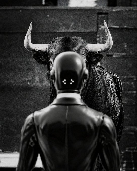 A humanoid figure faces a bull with prominent horns in a stark black-and-white scene, with the bull towering behind the robot-like figure whose back is to the viewer. The image metaphorically captures the post's sentiment, suggesting the bot is confronting or navigating the powerful, upward charge of a rising bull market.