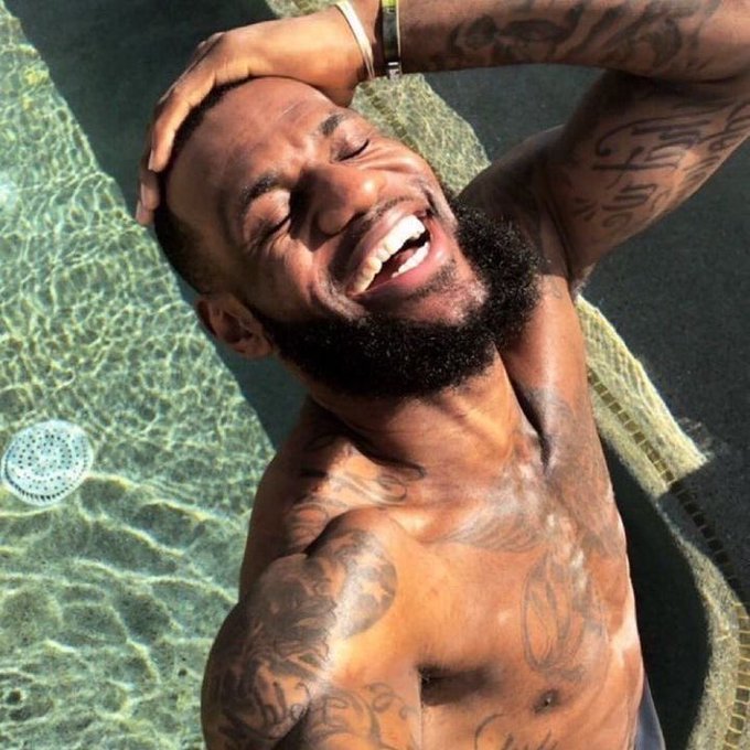 The image shows a man with tattoos taking a picture of himself at a pool, holding his head up above water while smiling. The caption reads "day 37 of posting selfie until megaeth hits launch price ... 7% (current price 0.04355)".
