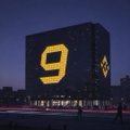 A nighttime photo of a large building with a glowing yellow number '9' on its facade.