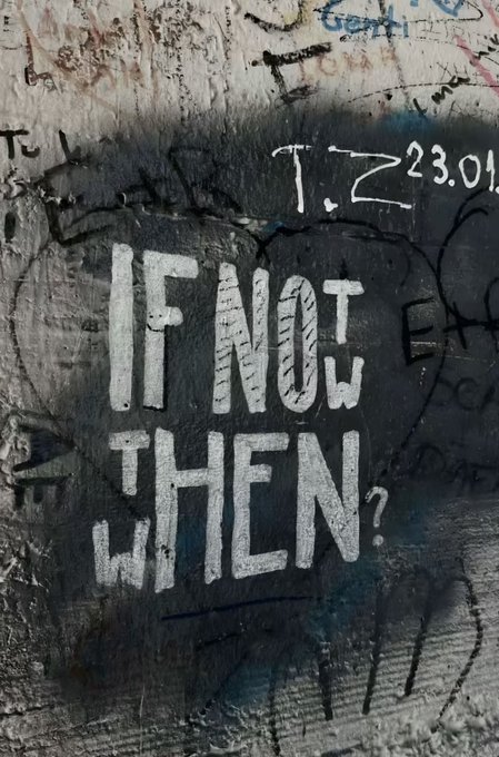White stenciled graffiti on a black-painted wall reads "IF NOT THEN WHEN?" alongside the initials "T.Z" and date "23.01," set against a weathered surface covered in layered tags and scribbles. The provocative message captures a sense of urgency that aligns perfectly with the post's prompt to "think about it," urging viewers to take action rather than postpone.