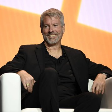 The image features a man sitting comfortably in a white chair, smiling at the camera. The background behind him has an orange and purple color scheme, which adds a vibrant touch to the scene. There are also several headlines related to cryptocurrency and Bitcoin that appear in the image, indicating that this could be a discussion or presentation about these topics.