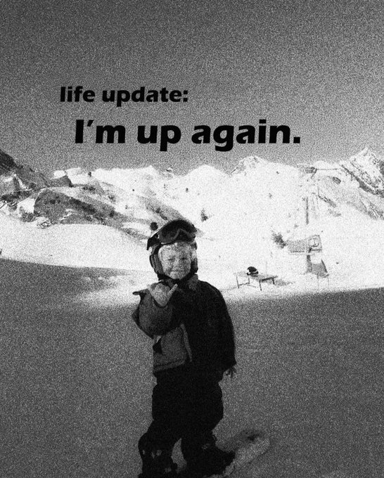 A black-and-white photo of a young child in ski gear standing on a snowy slope, with overlaid text reading 'life update: I'm up again.'