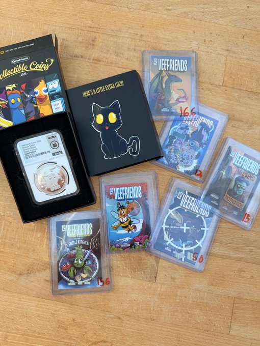 Collection of graded Pokémon trading cards including Mewtwo and various 'LV.X' and 'LV.X Legends' cards, along with a NYCC Collectible Coins box and a 'Here's a Little Extra Luck' black box, displayed on a wooden floor.