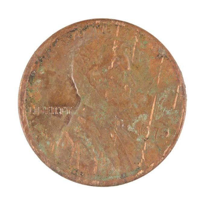 The reverse (tails) side of a worn 1935 US Lincoln wheat penny, showing the Lincoln Memorial design with visible wear, scratches, and green patina/oxidation spots across the copper surface.