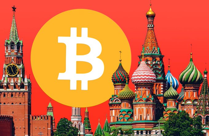 The image features the iconic St. Basil's Cathedral and the Kremlin's Spasskaya Tower against a red background, with a large Bitcoin logo prominently displayed in an orange circle. It illustrates Russia's Bank of Russia approving $BTC, $ETH, and $USDT for public trading on domestic exchanges.