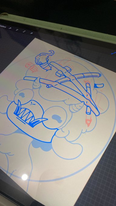 A photograph of a tablet displaying a blue line drawing of a cartoonish skull character with an eyepatch and a sword, resting on a dark gridded surface.