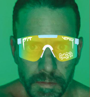 The image depicts a man wearing yellow sunglasses with a white "V" and "MOG" label, against a green background. There are no other texts or objects present in this particular photo. The focus of the image seems to be on the sunglasses themselves and their design rather than any accompanying information about a marketcap, currency, or event.