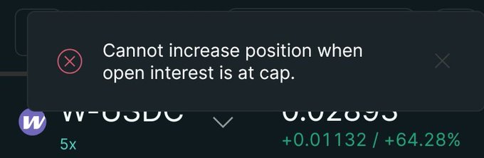 A trading app error notification reading 'Cannot increase position when open interest is at cap.' displayed over a cryptocurrency ticker showing W-USDC with a +64.28% gain.