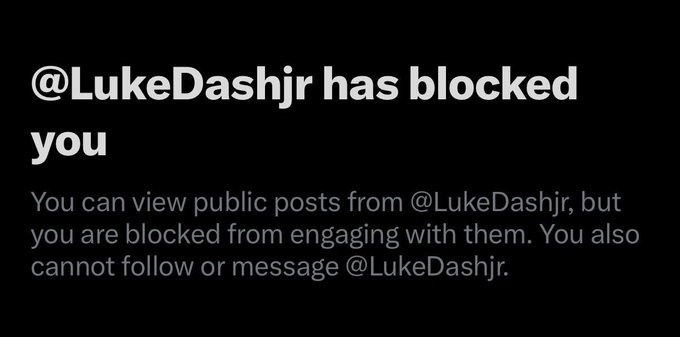A screenshot of a social media notification stating '@LukeDashjr has blocked you' with additional text explaining the user can view public posts but is blocked from engaging, following, or messaging the account.
