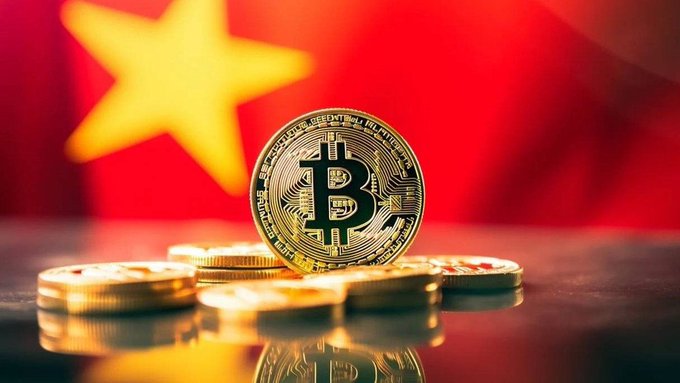 Photograph of a gold Bitcoin coin standing upright on a pile of coins, with the flag of Vietnam blurred in the background.