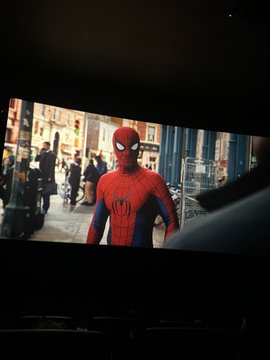 In the bustling city, a figure donned in a red suit with spider emblems, epitomizes vigilance and heroism. The image encapsulates a moment of everyday life in the city with the mysterious character keeping watch, juxtaposed with the post "Madi lifemaxi" which seems to celebrate individual strength and perseverance in a crowded world.