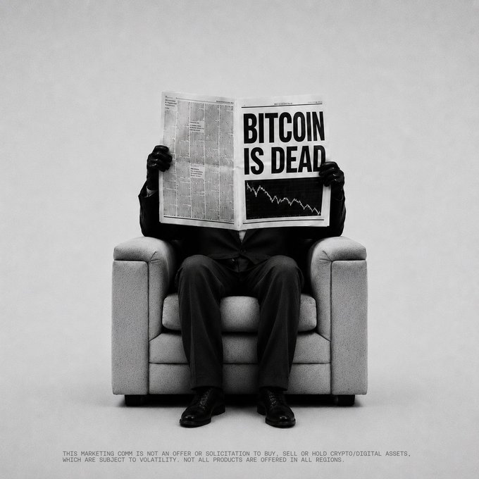 A black and white illustration shows a suited figure sitting in an armchair reading a newspaper headlined 'BITCOIN IS DEAD' with a downward price chart.