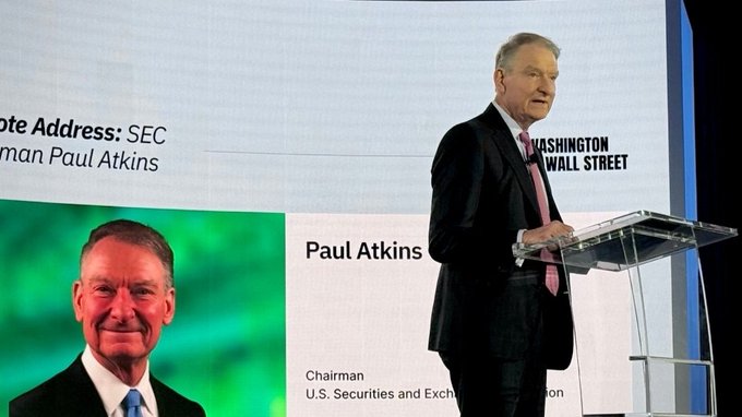 Paul Atkins, Chairman of the U.S. Securities and Exchange Commission, speaks at a podium at a 'Washington Wall Street' event, with his photo displayed on a presentation screen.