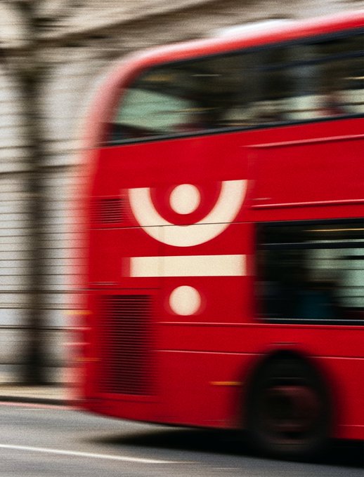 A motion-blurred photo of a red double-decker bus speeding through a street.