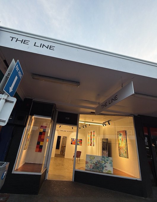 The storefront of "THE LINE" gallery at address 318 displays various abstract paintings and artworks through its brightly lit windows, with a "PAY HERE" sign mounted on the exterior. The image contrasts sharply with the post's bleak depiction of an enduring NFT bear market—the traditional art gallery stands as a quiet reminder that physical artwork, unlike volatile digital tokens, maintains tangible value even amid crypto's prolonged downturn.
