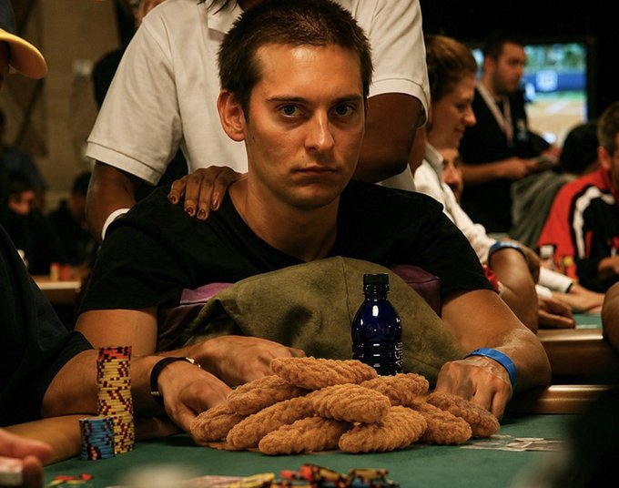 A young man with a serious expression sits at a green felt poker table, arms wrapped around a massive pile of casino chips with a water bottle behind him, embodying the post's "locked in" poker grind as he prepares to battle it out in the Solana and Robinhood markets.